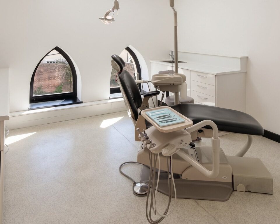 Bright treatment room in the chapel, with a dental chair beside two pointed Gothic windows