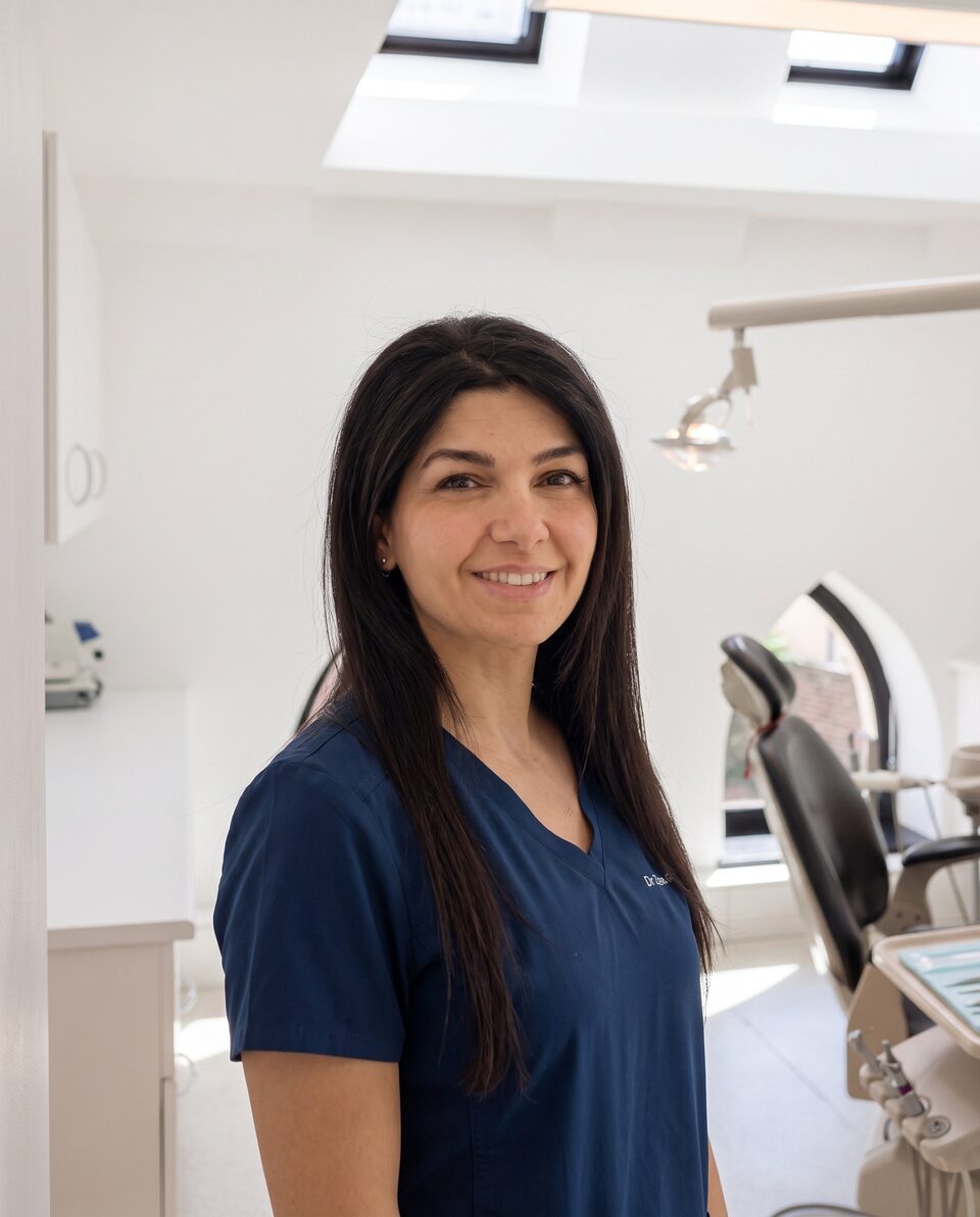 Dr Zena Al-Ansari in navy scrubs, smiling in a treatment room